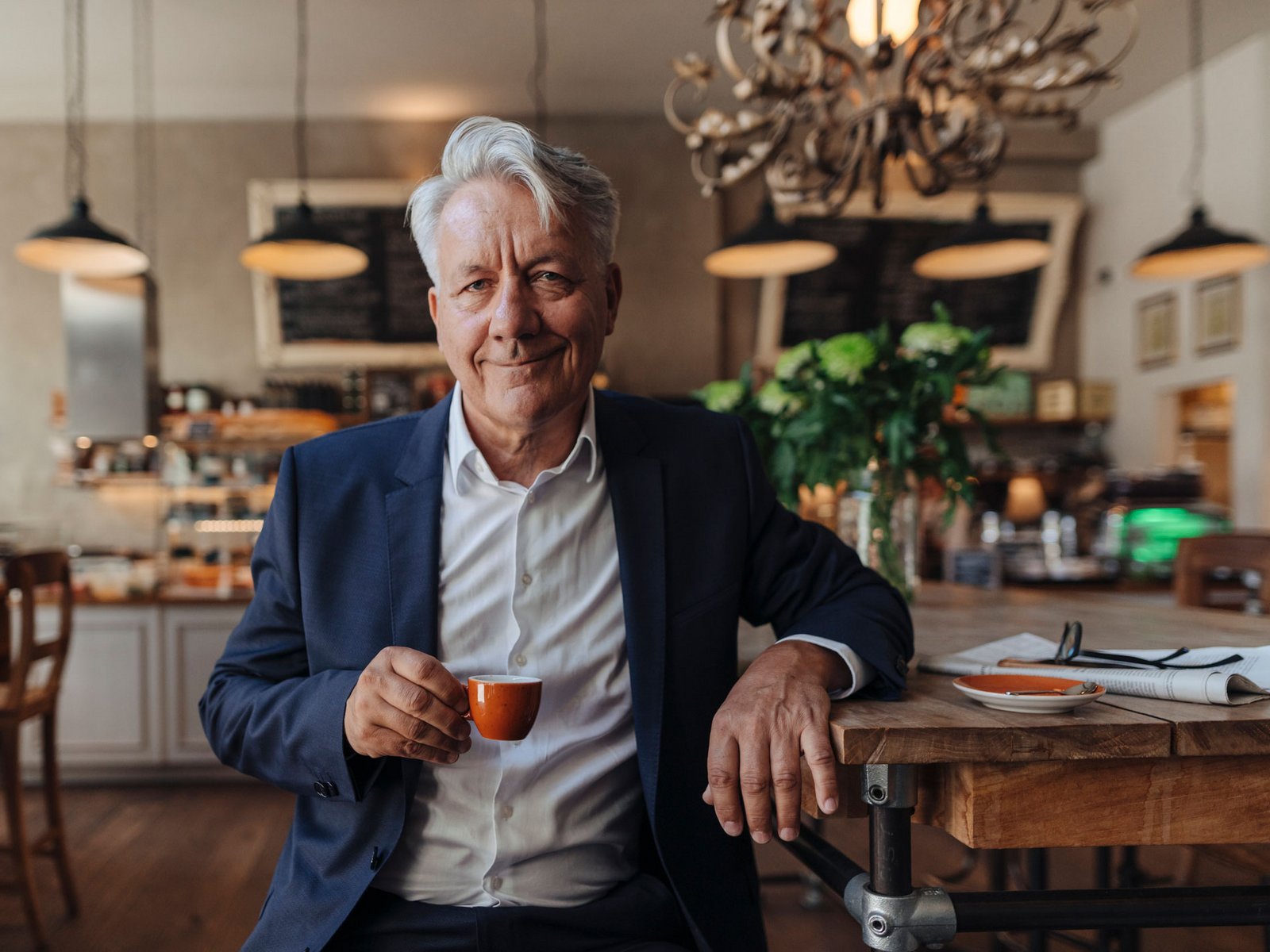 Mann lehnt an Bar mit Kaffeetasse in der Hand