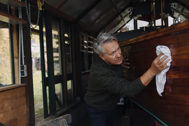 Mann poliert den hölzernen Rumpf seiner Jacht
